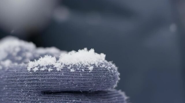 Delicate snowflakes settle on a soft woolen surface, highlighting intricate frozen patterns against the cozy texture of winter clothing.