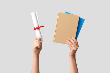 Female hands holding diploma and notebooks on white background