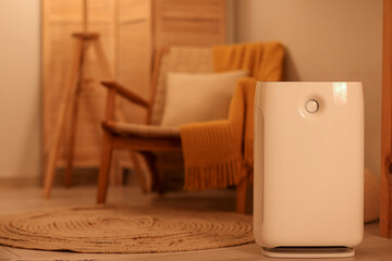 Big humidifier near armchair on floor in living room at evening