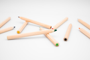 Scattered wooden colored pencils on white background