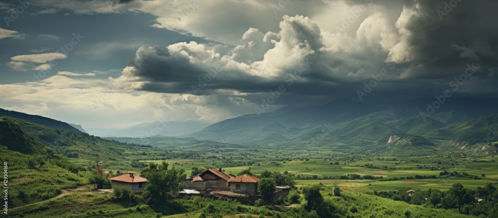 Poster Dramatic landscape featuring a rustic farmhouse in the foreground surrounded by lush green fields under a moody, cloudy sky with distant mountains.