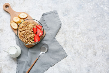 Wooden cutting board, bowl with tasty granola, banana and berries on grunge background