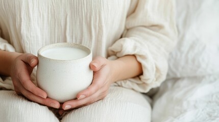 A serene and reflective moment as a woman sits in a quiet cozy bedroom holding a glass of milk in one hand and a book in the other
