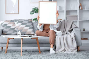 Young woman sitting on sofa with frame in living room