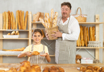 Baker dad and daughter are standing near product range in bakery kitchen.