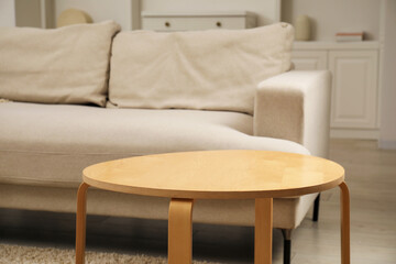Stylish wooden coffee table near sofa in living room