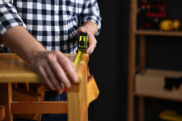 Repairman measuring wooden stool in workshop, closeup