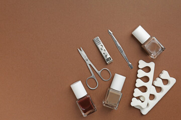 Set of pedicure tools on brown background, flat lay. Space for text