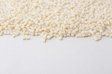 Pile of plastic granules on white background, closeup. Space for text