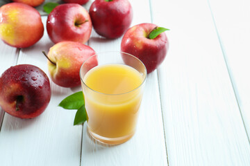 Refreshing apple juice in glass and fruits on white wooden table, closeup. Space for text