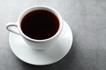 Refreshing black tea in cup on grey table, closeup. Space for text