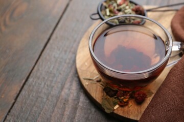 Delicious herbal tea and dry leaves on wooden table, closeup. Space for text