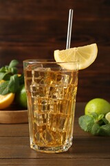 Refreshing iced tea with slice of lemon, lime and mint on wooden table, closeup