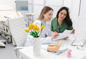 Gynecologist reviewing ultrasound of her pregnant patient while prenatal screening 1st trimester in gynecology clinic. Pregnancy management