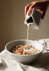 Female pouring milk into bowl of cereal