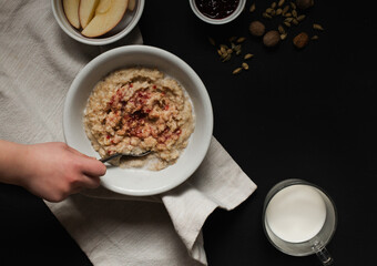 Child stirring warm bowl of oatmeal with fruit