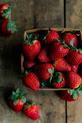 Fresh, ripe strawberries in a rustic wooden basket on a table.