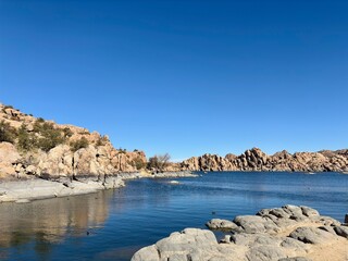 Rocky shoreline and calm blue waters of Watson Lake in Prescott, AZ