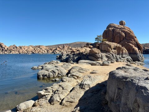 Rocky shoreline of Watson Lake in Prescott, AZ, with calm blue water