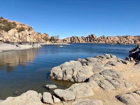 Rocky shoreline of Watson Lake in Prescott, AZ with calm blue water