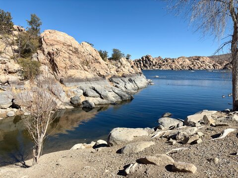 Rocky shoreline and calm blue waters of Watson Lake in Prescott, AZ