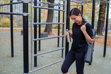 Fototapeta premium Girl with yoga mat and bottle before training on the ground in park