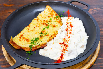 Savory omelette served with creamy yogurt sauce and herbs