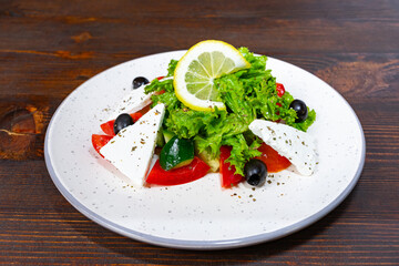 Fresh salad with feta, olives, and lemon on wooden table