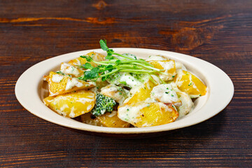 Savory baked potatoes with creamy sauce and greens on wooden table
