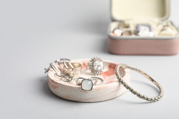 Tray and organizer with beautiful silver jewelry on grey background