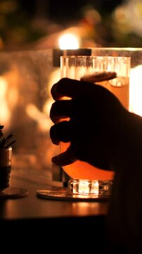 Serata romantica, la mano sul calice di un Cocktail e il calore del fuoco delle luci e del fuoco sullo sfondo.
Un Cocktail servito in una location piena di luci e di emozione.