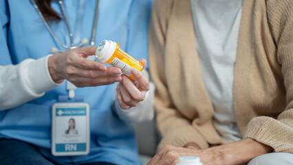 Asian Caregiver nurse showing pills bottle drugs and consultant to senior woman patient.Doctor or...