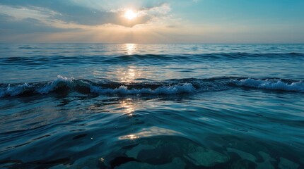 Obraz premium Tranquil ocean scene with sunlight reflecting on calm waters and gentle waves under a serene sky during sunrise or sunset.