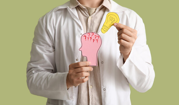 Male inventor with paper human head and light bulb on green background, closeup