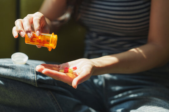 Woman pouring pills from prescription bottle into hand