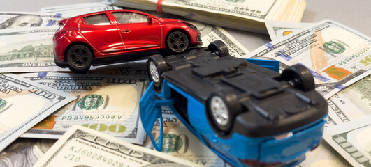 Toy cars in accident on a background of 100 dollar bills