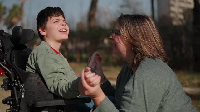 Disabled child sharing a moment of joy with his mother in the park