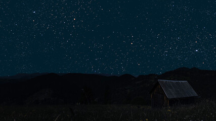 A movement of stars in the night sky with the view of mountains..