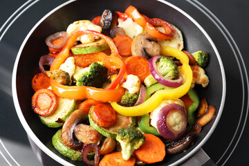 Frying pan with mix of vegetables and mushrooms on cooktop, closeup