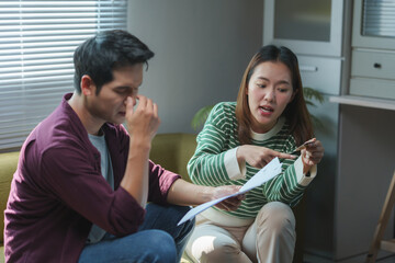 Stressed asian couple arguing about credit card bills at home