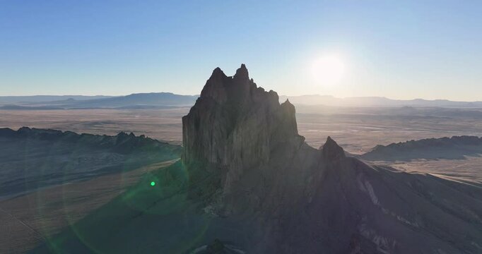 An unworldly, high-contrasted aerial shot of the sacred &ldquo;Ship Rock&rdquo;, a massive, monolithic rock butte, towering above the high desert plain of the Navajo Nation, in New Mexico, as the sun sets behind.