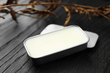 Natural solid perfume and dry branch on black wooden table, closeup