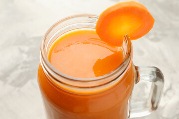 Fresh carrot juice in mason jar on gray table, closeup