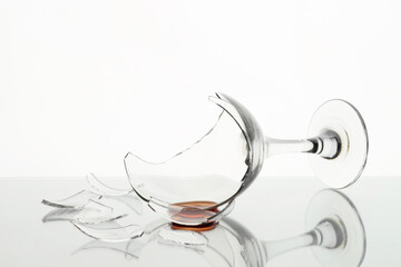 Pieces of broken glass with wine on table against white background, closeup