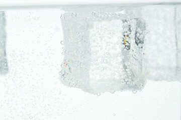 Refreshing soda water with ice cubes as background, closeup