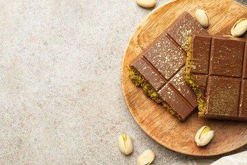 Pieces of Dubai chocolate bar with pistachios and knafeh on grey table, top view. Space for text