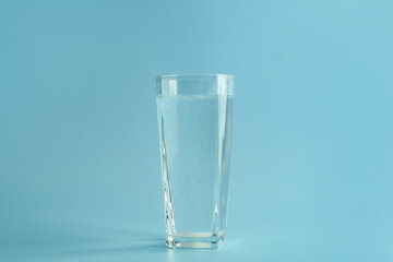 Soda water in glass on light blue background