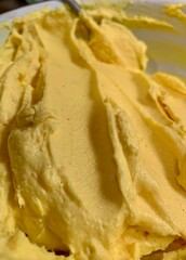 Smooth and creamy butter is skillfully blended in a well-lit kitchen, highlighting its rich yellow hue. The scene reflects a cozy, homey atmosphere