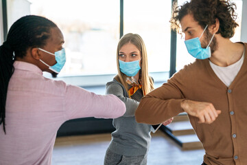 Business people, entrepreneurs with protective face masks elbow bumping while greeting on meeting