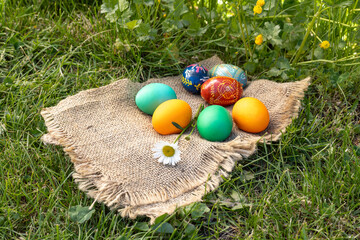 Easter eggs and a sackcloth bag on green grass.